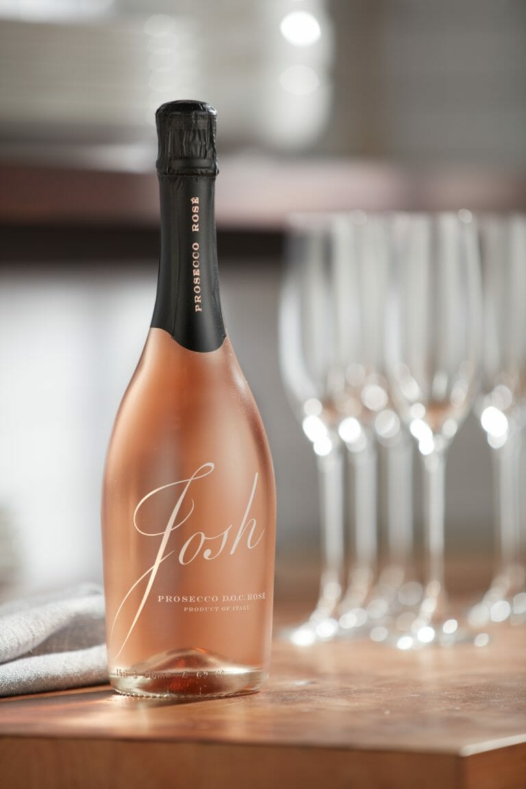 bottle of josh cellars rose prosecco sitting on table with champagne flutes